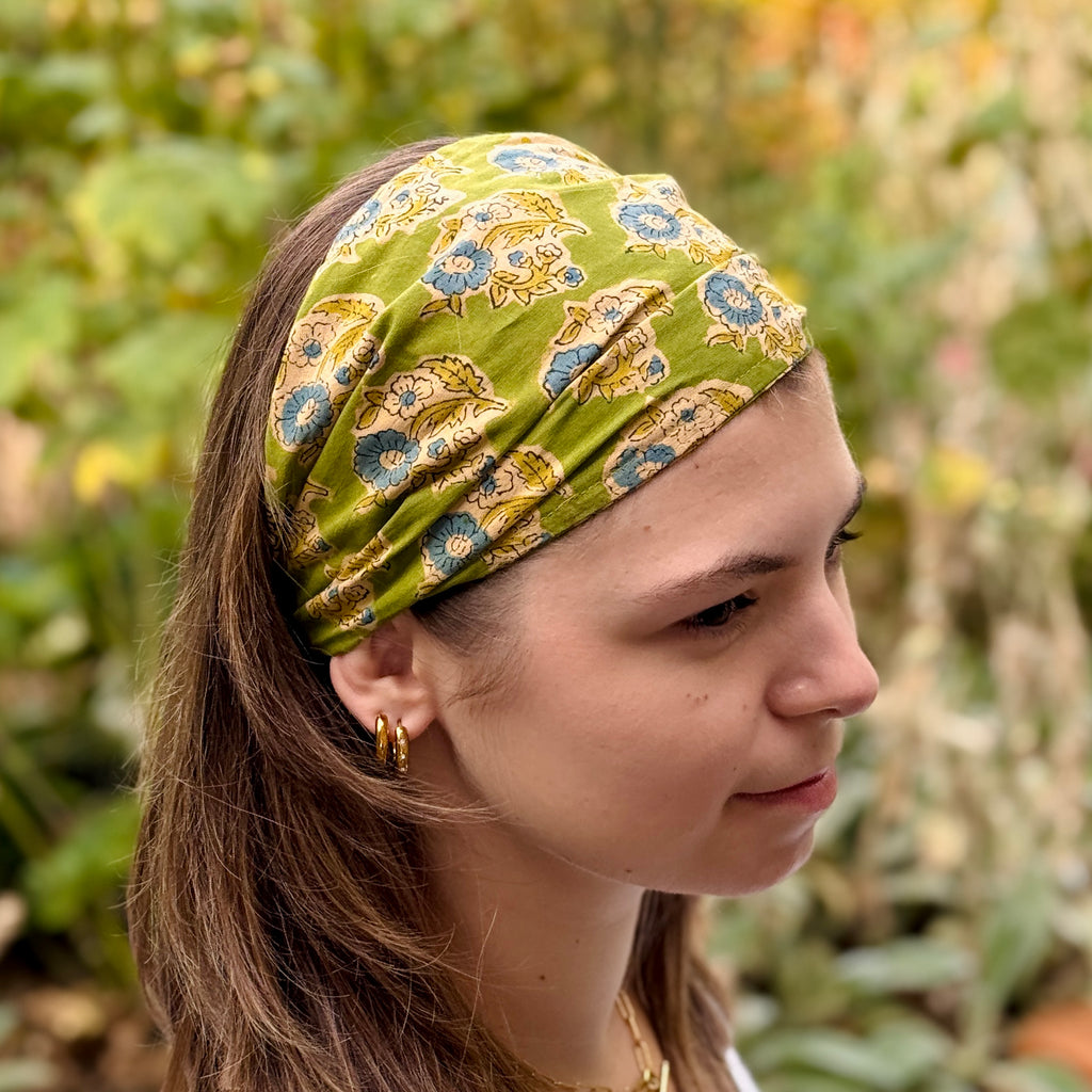 Woman wearing a green patterned headband with a blurred natural background