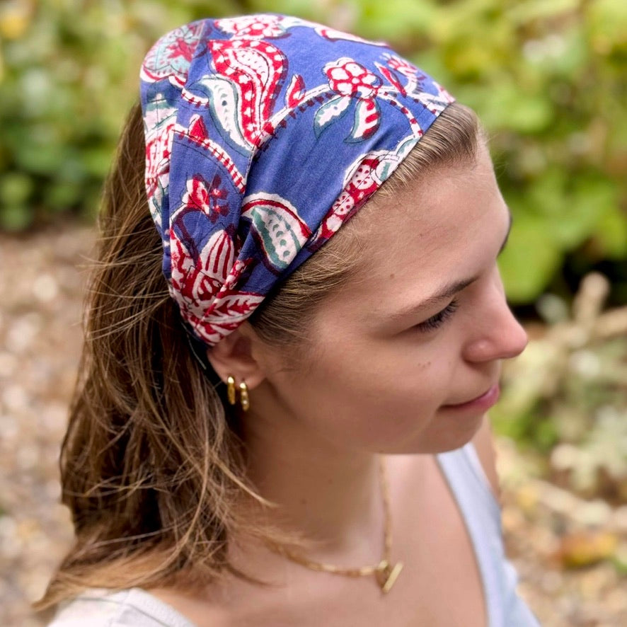 Woman wearing a blue patterned headband with a blurred natural background