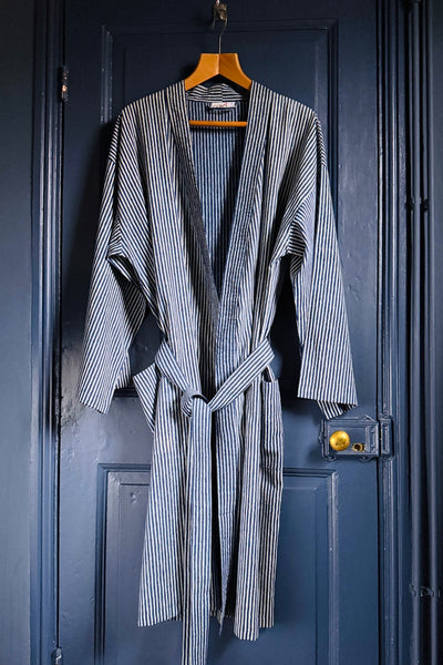 Striped robe hanging on a wooden hanger against a blue door.