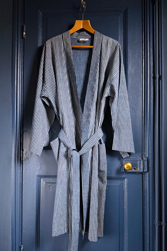 Striped robe hanging on a wooden hanger against a blue door.