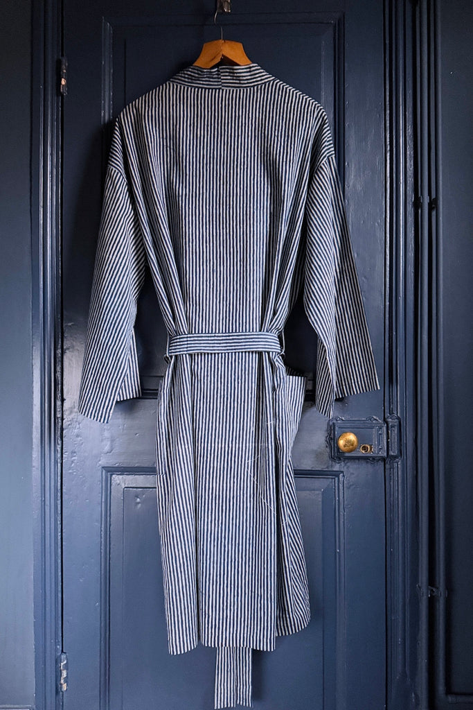 Striped robe hanging on a wooden hanger against a dark blue door.