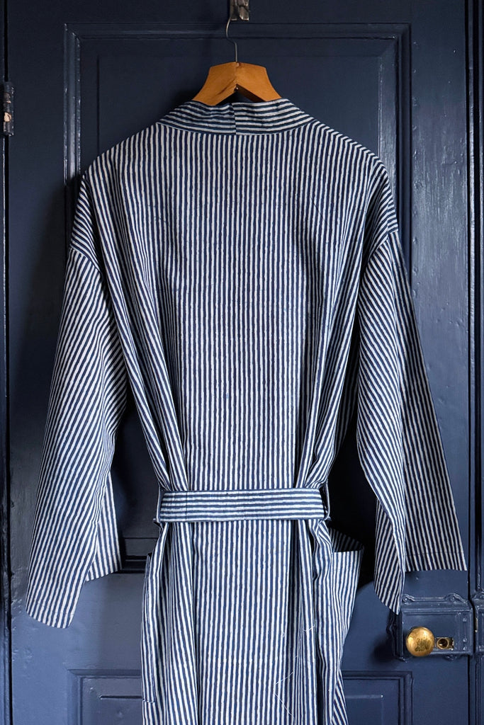Striped robe hanging on a wooden hanger against a dark blue door.