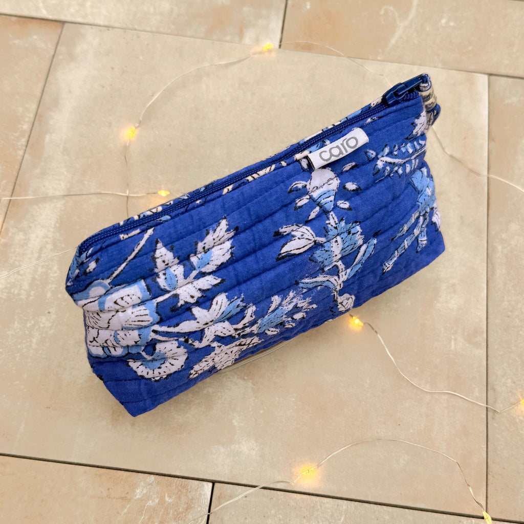 Blue floral make up bag with quilt stitching on a tiled floor