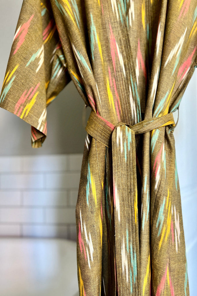 Olive green robe with colorful abstract pattern on a blurred indoor background