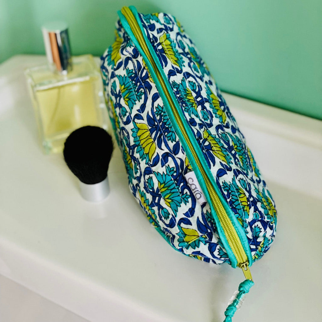 Patterned toiletry bag on a bathroom counter with perfume and brush