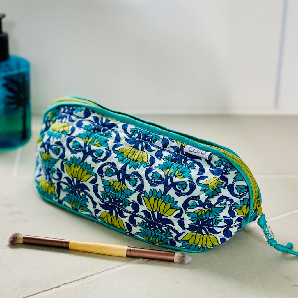 Patterned toiletry bag on a bathroom counter with perfume and brush