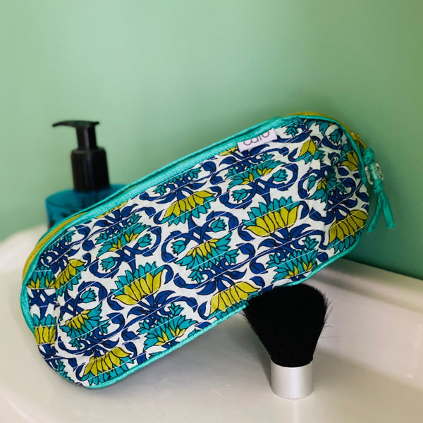 Patterned toiletry bag on a bathroom counter with perfume and brush